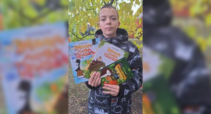 Ілля Отрошенко тримає в руках трилогію книг «Велика лісова пригода».