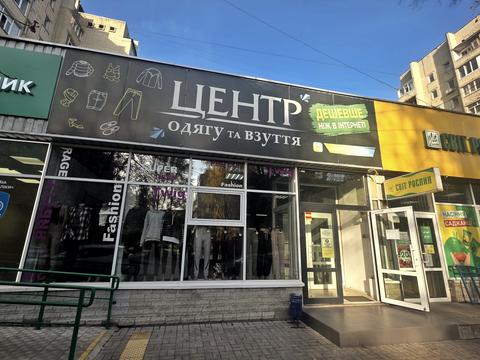 Магазин «Центр одягу та взуття» з написом «Дешевше ніж в інтернеті» на Засумській у Сумах, поруч вхід до «Світу рослин»
