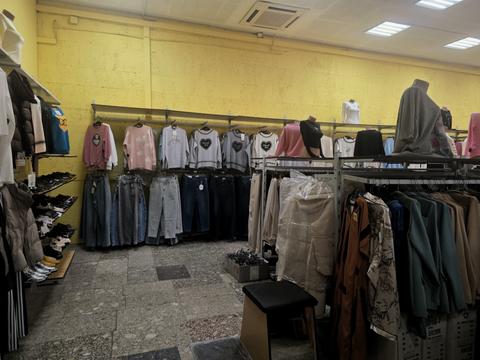 Зала магазину «Конфі Склад» у Сумах: жовті стіни, ряд светрів над джинсами, стійки з сорочками, манекени, полиця з туфлями