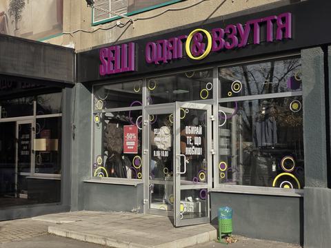 Вхід до магазину SELLI у Сумах: чорна вивіска з фіолетовими літерами, на дверях графік 9:00–19:00 і напис «Обирай те, що любиш»