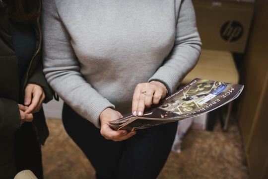 Руки гортають сторінки архівного альбому фонду Хесед Хаїм