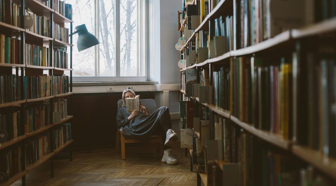 Дівчина читає книгу в бібліотеці