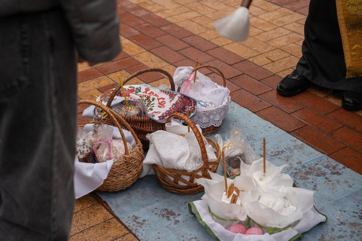 Священник щедро кропить великодні кошики