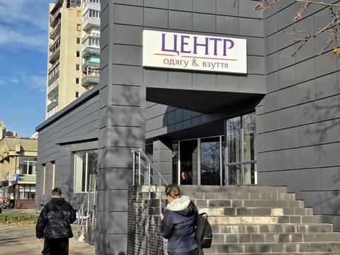Сіра будівля магазину «Центр одягу & взуття» у Сумах, широкі сходи з поруччям до входу