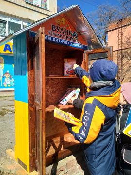 khlopets klade knyhu v minibiblioteku Хлопчик кладе книгу в мінібібліотеку
