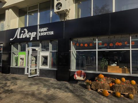 Магазин «Лідер. Одяг і взуття» на Харківській у Сумах: чорний фасад, банкомати біля входу, гарбузи й солома перед вітриною