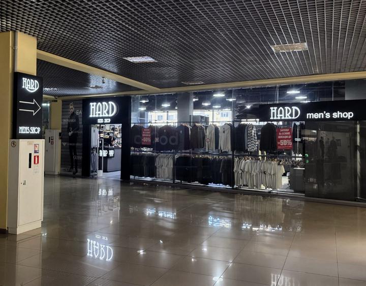 Магазин HARD men’s shop у ТРЦ «Лавина» в Сумах: скляна вітрина з чоловічими светрами й сорочками, таблички «−50%», світлова вивіска