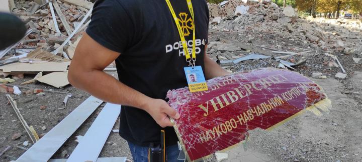 чоловік тримає в руках понівечену табличку з назвою