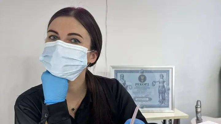 Оксана Тіхонова сидить у кабінеті а позаду неї сертифікат, що засвідчує встановлення рекорду