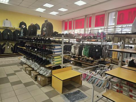 Полиці з кросівками й черевиками в магазині «Конфі Склад» у Сумах, дитячі рюкзаки, кошик із капцями, чоловічі куртки на стіні