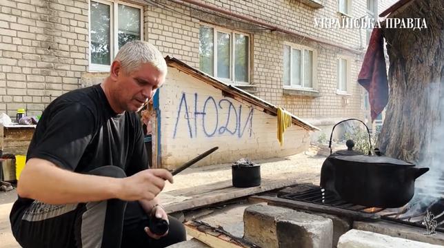 Чоловік у Сіверську готує їжу на подвір'ї.