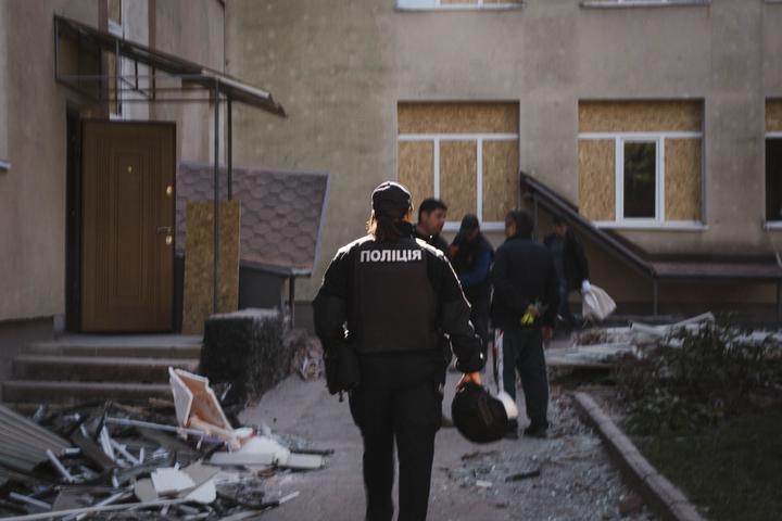 Офіцерка безпеки оглядає територію школи. Зліва від неї — корпус школи, біля нього — будівельне сміття
