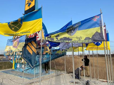 Військові встановлюють стяги довкола стели.