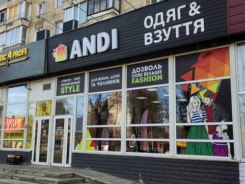Вхід до магазину ANDI «Одяг & Взуття» у Сумах: чорна вивіска, вітрини з написами STYLE і FASHION, біля дверей генератор