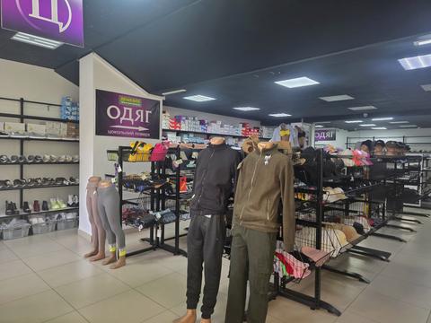 Перший поверх магазину «Дешевше ніж в інтернеті» у Сумах: полиці зі взуттям, кошики з шапками, манекени, табличка «Одяг, цокольний поверх»