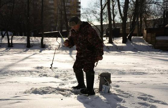 Рибалка на Пслі стоїть і тримає в руках вудку.