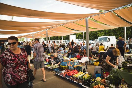 На базарі багато людей продають свіжі овочі та фрукти