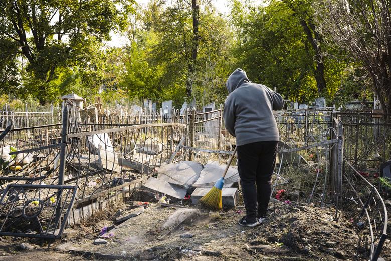 Працівниця «Спецкомбінату» прибирає пошкоджену могилу на Центральному кладовищі