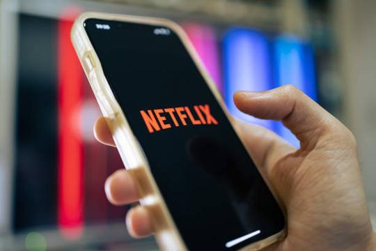 Людина тримає в руках телефон. На ньому відкрила нетфлікс.