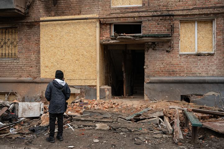 Хлопчик біля зруйнованого росіянами підʼїзду свого будинку