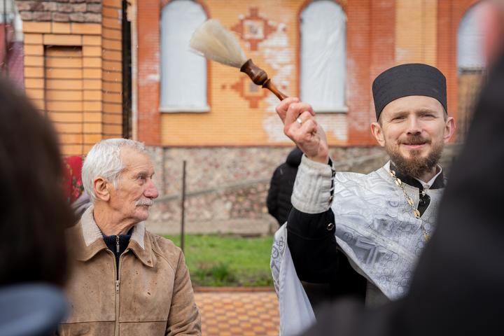 Священник кропить фотографа у черзі