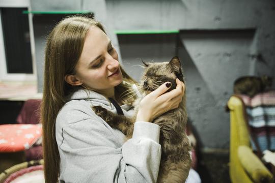 Волонтерка Маріанна тримає котика на руках і з любов'ю дивиться на маленького.