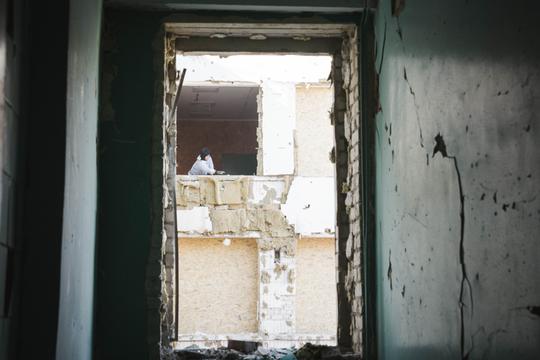Жінка у вікні без рами прибирає будівельне сміття