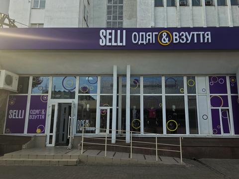 Магазин SELLI «одяг & взуття» у Сумах: фіолетова вивіска, вітрини з кольоровими колами, пандус із поруччям біля входу